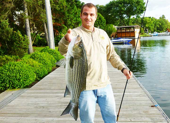 ryan ordemann with a huge striped bass he caught in a lake